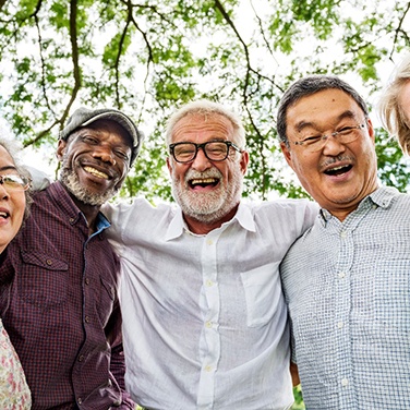 Diverse group of older adults under a tree smiling at the camera